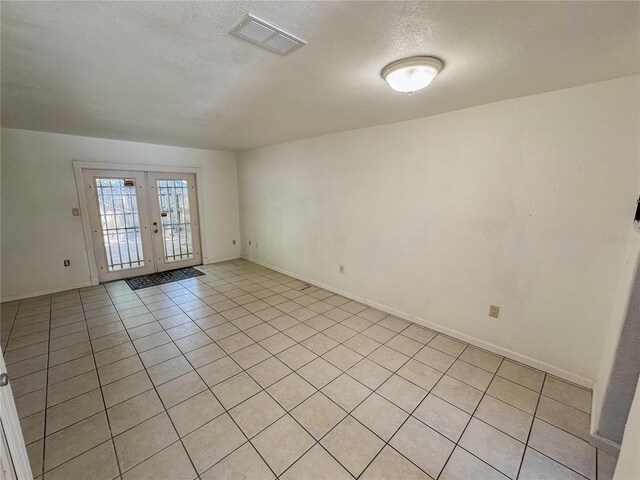 3935 SW 26th Ter Unit 3935A, Gainesville, FL 32608 - spare room with a textured ceiling, french doors, baseboards, light tile patterned floors, and visible vents