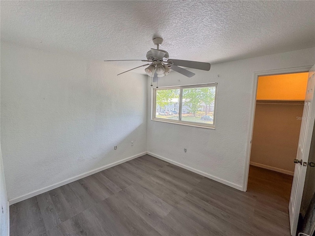 3935 SW 26th Ter Unit 3935A, Gainesville, FL 32608 - unfurnished bedroom with baseboards, a textured ceiling, dark wood finished floors, and a walk in closet