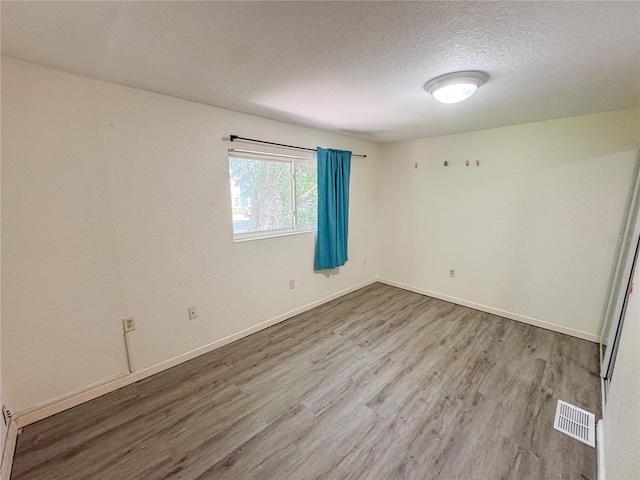 3935 SW 26th Ter Unit 3935A, Gainesville, FL 32608 - unfurnished room with baseboards, a textured ceiling, visible vents, and wood finished floors
