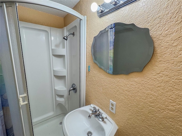 3935 SW 26th Ter Unit 3935A, Gainesville, FL 32608 - bathroom featuring a textured wall, a shower stall, and a sink