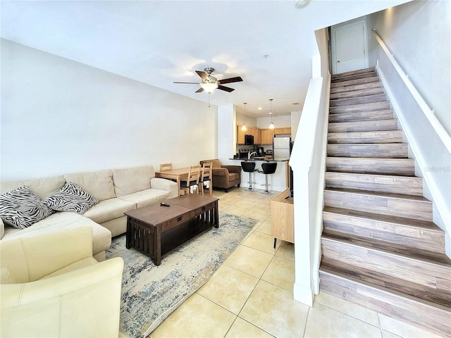 living area featuring ceiling fan, stairs, and light tile patterned floors