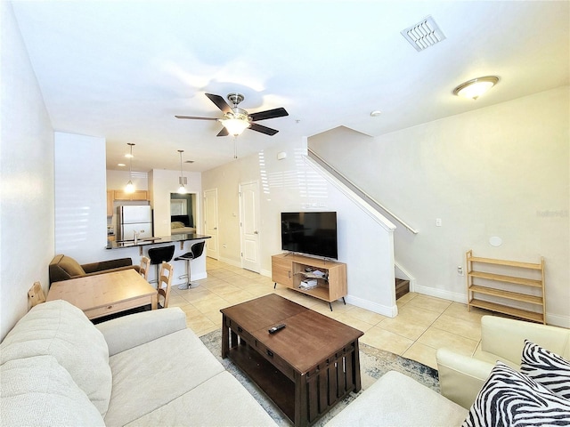 living area with light tile patterned floors, stairway, ceiling fan, and baseboards