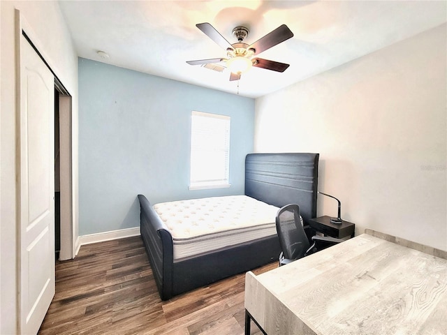bedroom with wood finished floors, baseboards, ceiling fan, and a closet