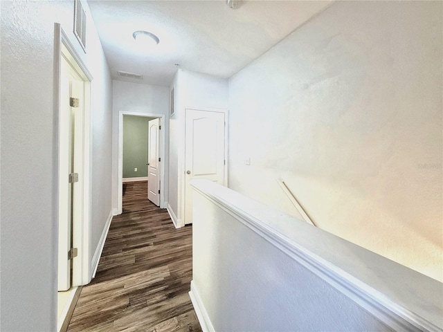 corridor featuring dark wood-style floors, baseboards, and an upstairs landing
