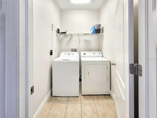 washroom with washer and clothes dryer, light tile patterned floors, and baseboards