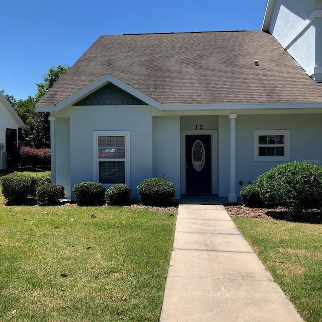 ranch-style house with stucco siding, roof with shingles, and a front yard