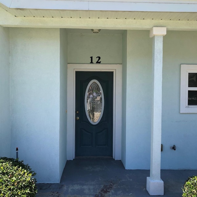 doorway to property featuring stucco siding