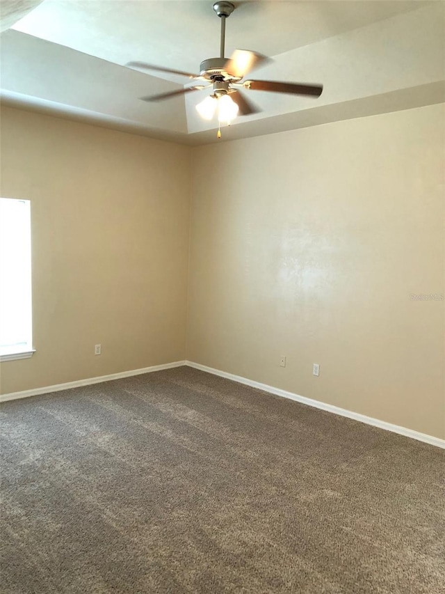 empty room with baseboards, a ceiling fan, and dark carpet