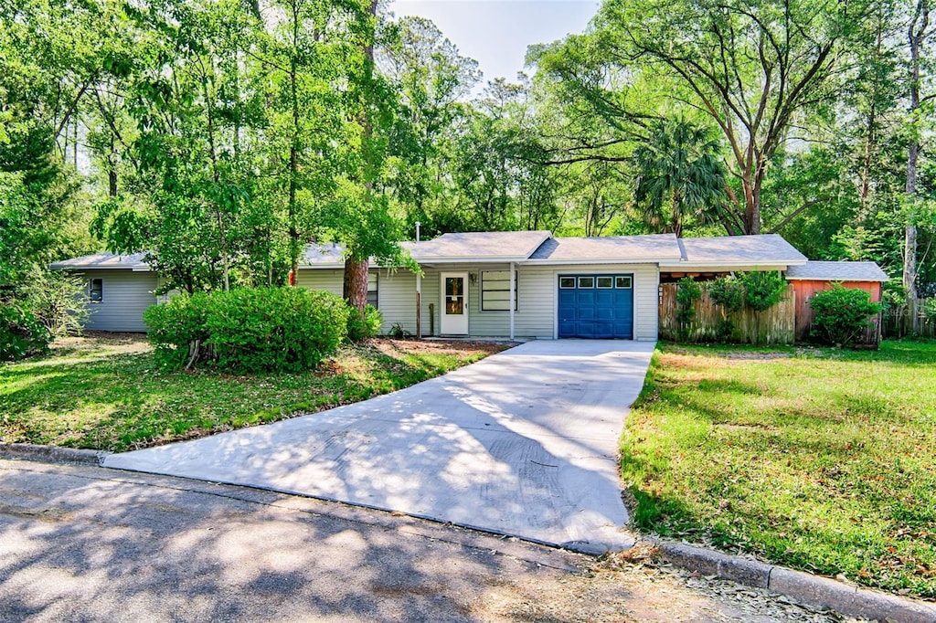 ranch-style home with concrete driveway, fence, a garage, and a front yard
