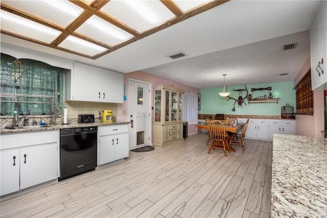 kitchen featuring black dishwasher, visible vents, white cabinets, and a sink