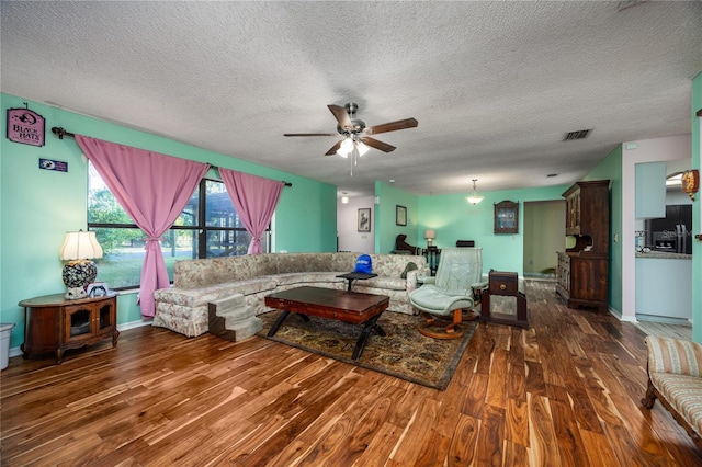 living room with visible vents, wood finished floors, a textured ceiling, and ceiling fan