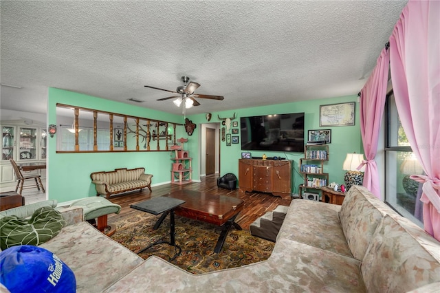 living area with wood finished floors, a textured ceiling, a ceiling fan, and visible vents