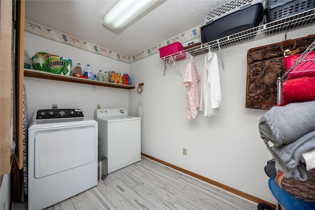 washroom featuring washing machine and clothes dryer, a textured ceiling, light wood-type flooring, baseboards, and laundry area