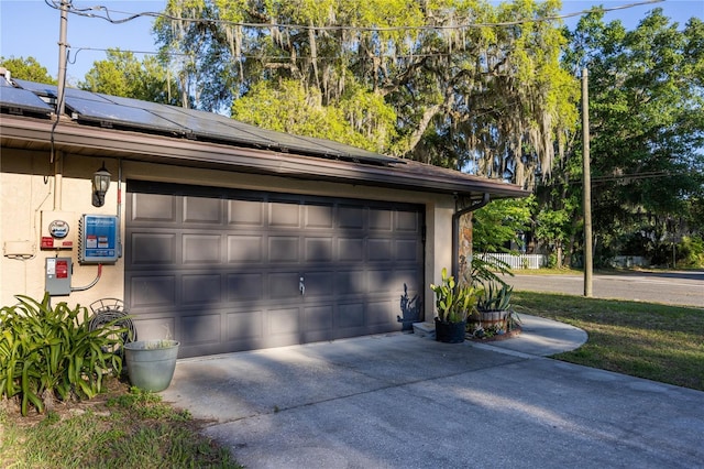 garage featuring roof mounted solar panels and concrete driveway