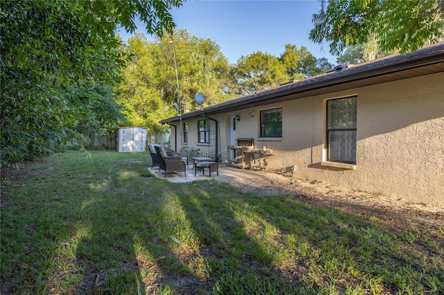 back of property featuring a storage shed, a yard, stucco siding, an outdoor structure, and a patio