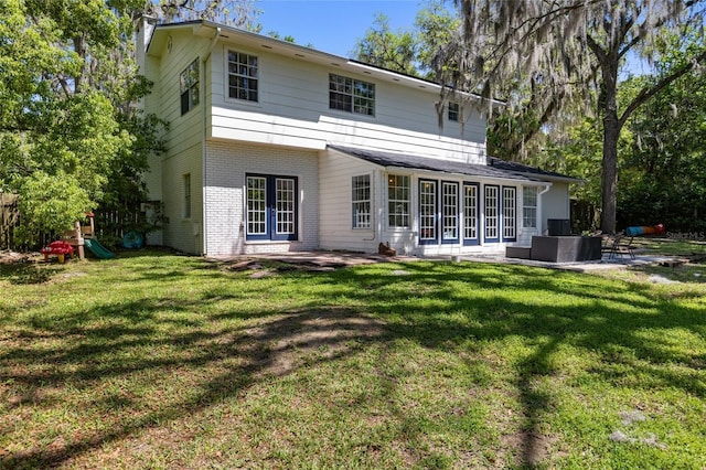 back of house featuring french doors, a patio, a yard, and brick siding