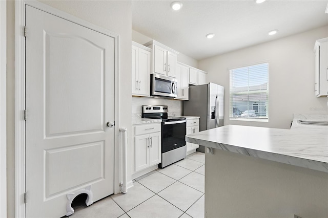 kitchen with light tile patterned floors, light countertops, white cabinetry, and stainless steel appliances