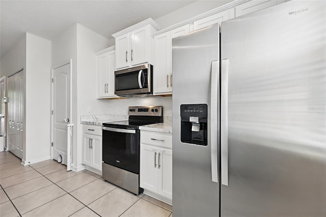 kitchen featuring appliances with stainless steel finishes, light tile patterned floors, and white cabinetry