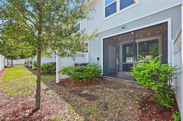 view of exterior entry with stucco siding and fence