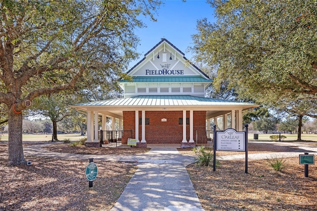 view of front of home with a standing seam roof, a porch, brick siding, and metal roof