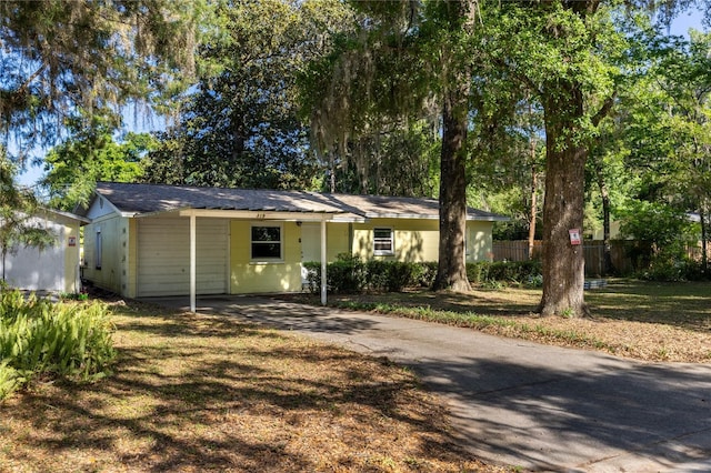 single story home featuring aphalt driveway and fence