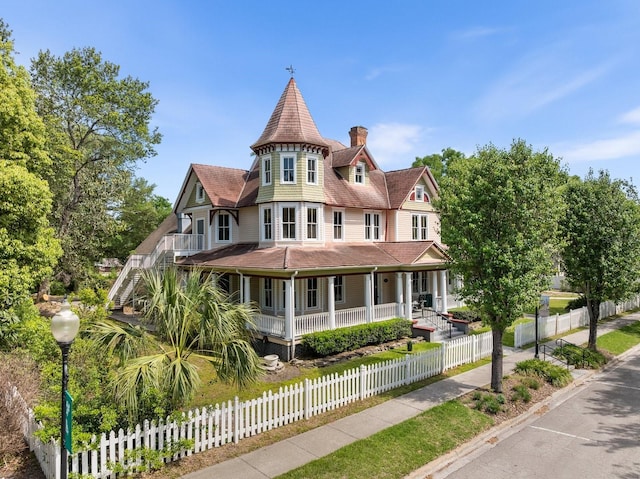 victorian home with a chimney, a porch, stairway, and a fenced front yard