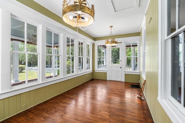 unfurnished sunroom with a notable chandelier, plenty of natural light, and hardwood / wood-style flooring
