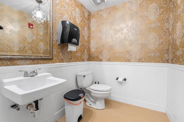 bathroom with toilet, visible vents, a wainscoted wall, and wallpapered walls