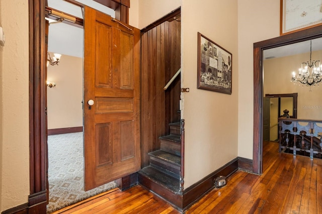 stairway with wood-type flooring, baseboards, and a chandelier