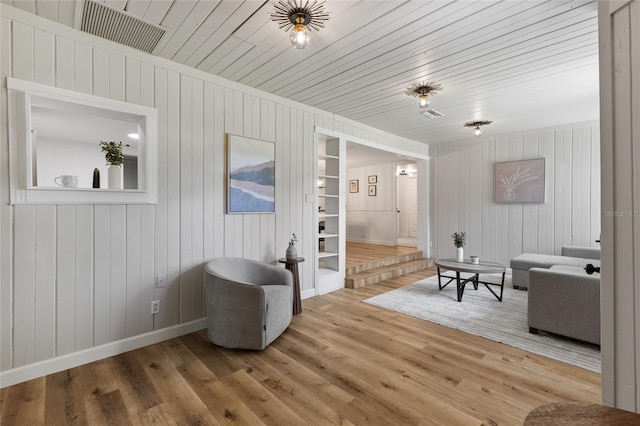 living area with wood walls, baseboards, and wood finished floors