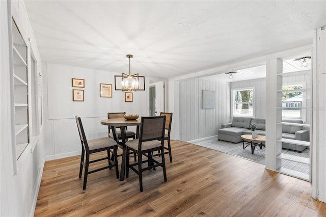dining room with light wood finished floors, baseboards, and a chandelier