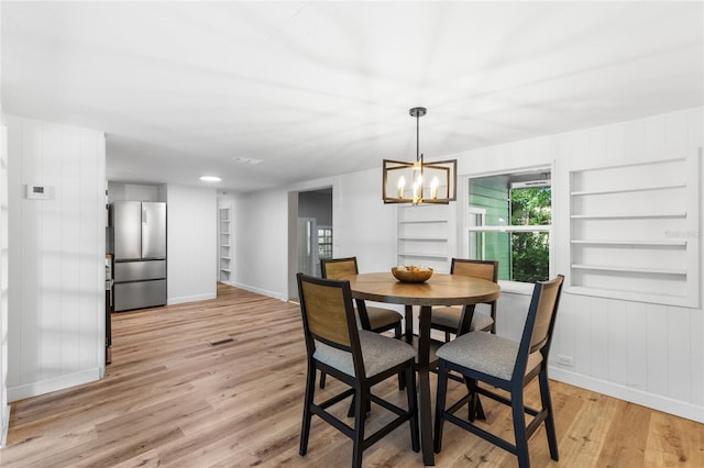 dining area with an inviting chandelier, baseboards, light wood-style floors, and built in shelves
