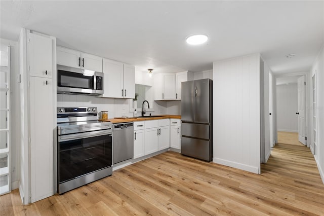 kitchen featuring appliances with stainless steel finishes, butcher block countertops, light wood-style floors, and a sink