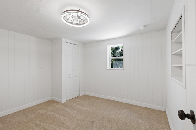 carpeted empty room featuring wooden walls and baseboards