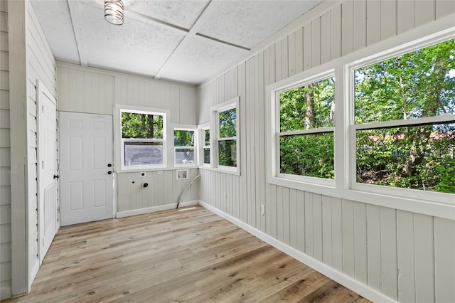 unfurnished sunroom with wooden walls, wood finished floors, and a wooden deck