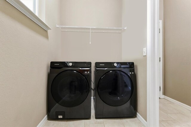 laundry room featuring tile patterned floors, baseboards, laundry area, and washing machine and clothes dryer