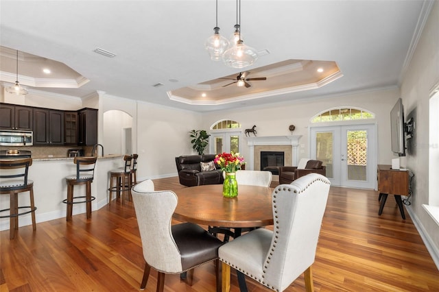 3624 SW 73rd Way, Gainesville, FL 32608 - dining room featuring a raised ceiling, a ceiling fan, wood finished floors, crown molding, and a glass covered fireplace