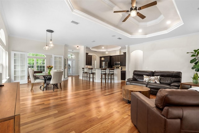 3624 SW 73rd Way, Gainesville, FL 32608 - living room with a tray ceiling, ceiling fan, ornamental molding, light wood finished floors, and arched walkways