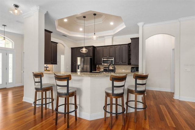 3624 SW 73rd Way, Gainesville, FL 32608 - kitchen featuring arched walkways, stainless steel appliances, dark brown cabinets, decorative backsplash, and a peninsula