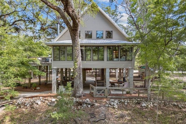 back of house featuring stairs, a sunroom, a patio, and metal roof
