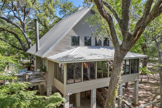 back of house featuring a sunroom, metal roof, and a deck