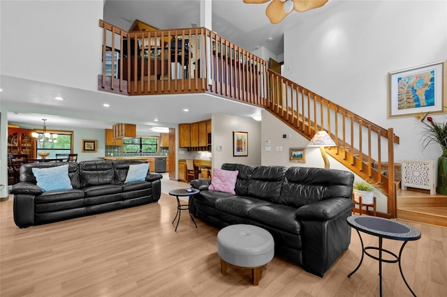 living room featuring recessed lighting, light wood-style floors, stairway, and a towering ceiling