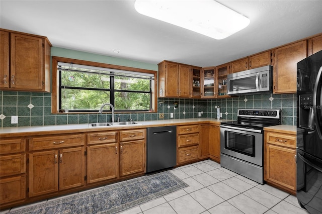 kitchen featuring brown cabinets, tasteful backsplash, stainless steel appliances, and a sink