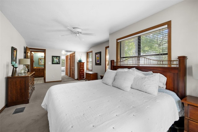 bedroom with visible vents, baseboards, light colored carpet, ceiling fan, and ensuite bath