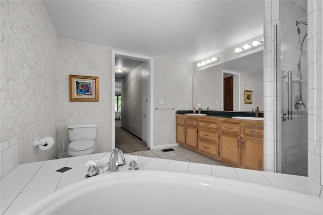 bathroom featuring a tile shower, tile patterned floors, double vanity, toilet, and a sink
