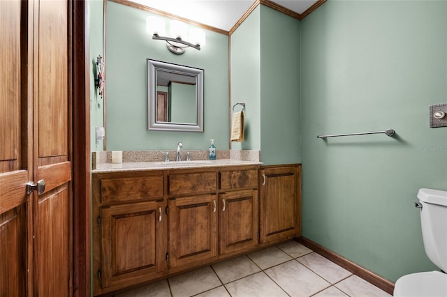bathroom with tile patterned flooring, toilet, vanity, crown molding, and baseboards