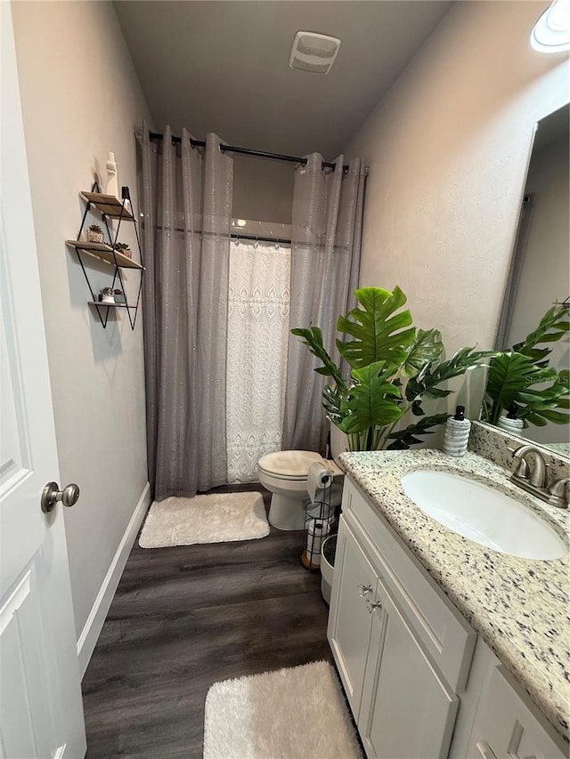 bathroom featuring vanity, toilet, visible vents, baseboards, and wood finished floors