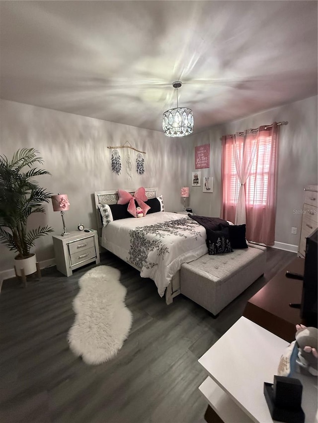 bedroom featuring dark wood finished floors and a chandelier