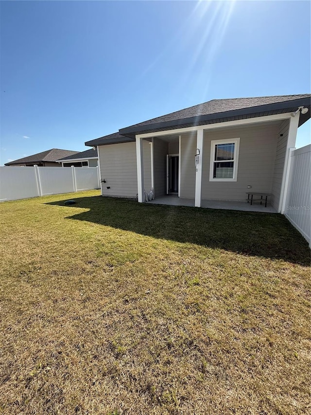 rear view of property featuring fence, a yard, and a patio area