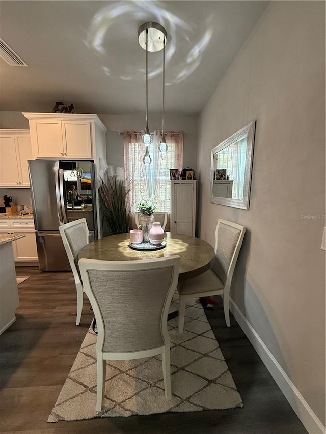 dining space with dark wood finished floors, visible vents, and baseboards